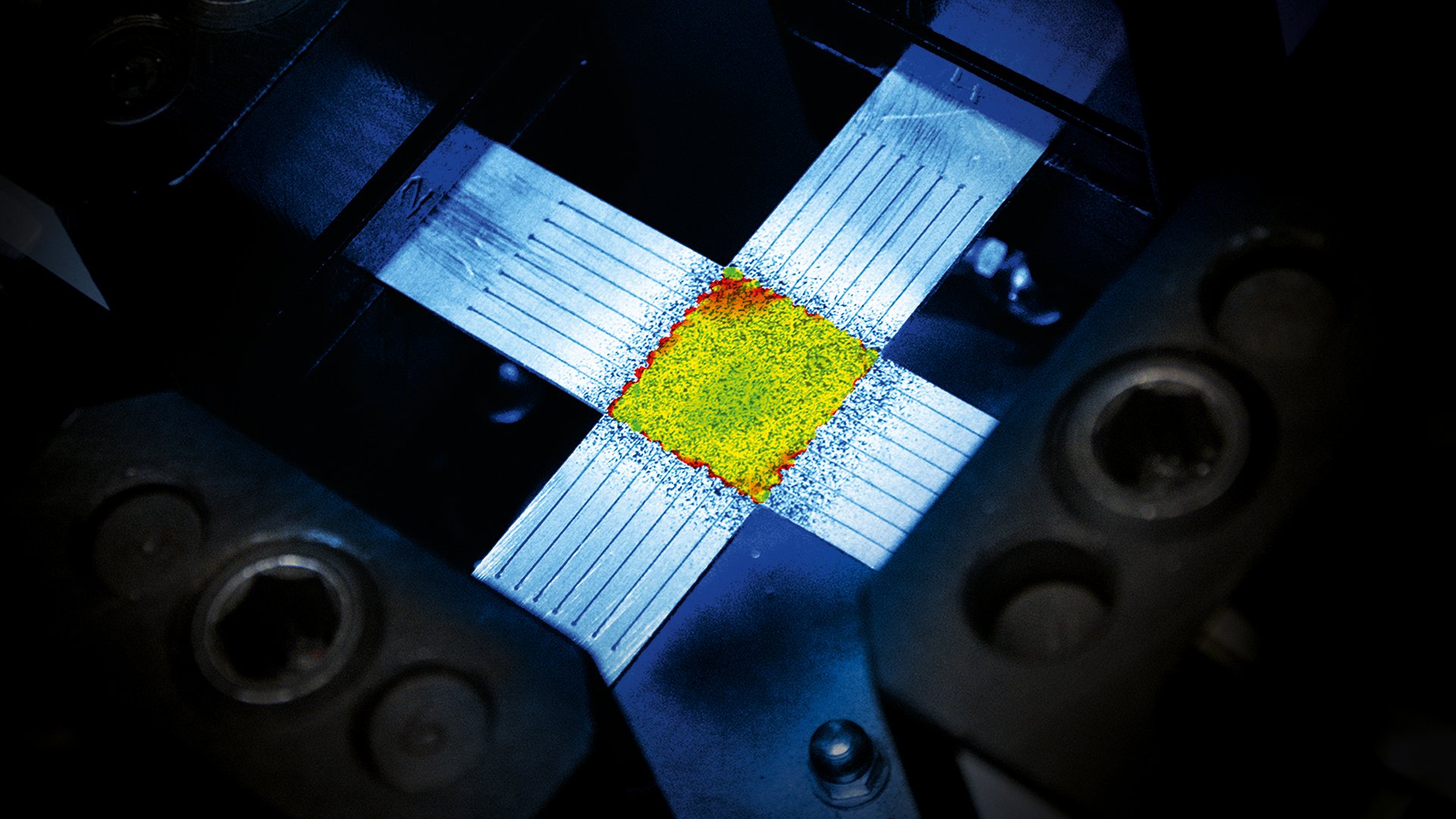 Cruciform biaxial tensile specimen with an ARAMIS strain field overlaid on the gauge region.