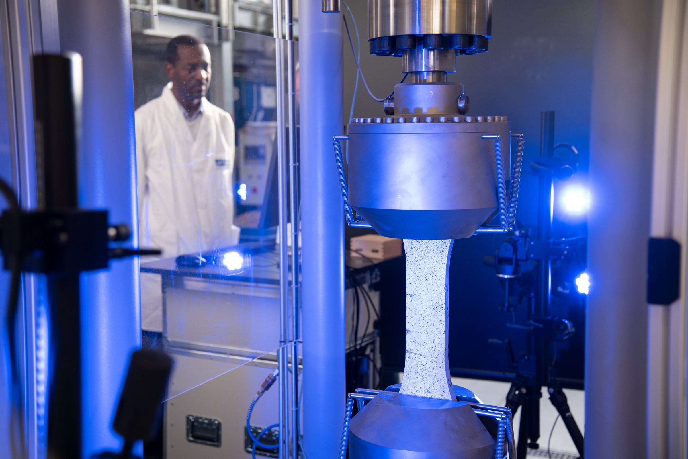 ARAMIS dogbone tensile specimen mounted in a universal test frame with full-field strain measurement.